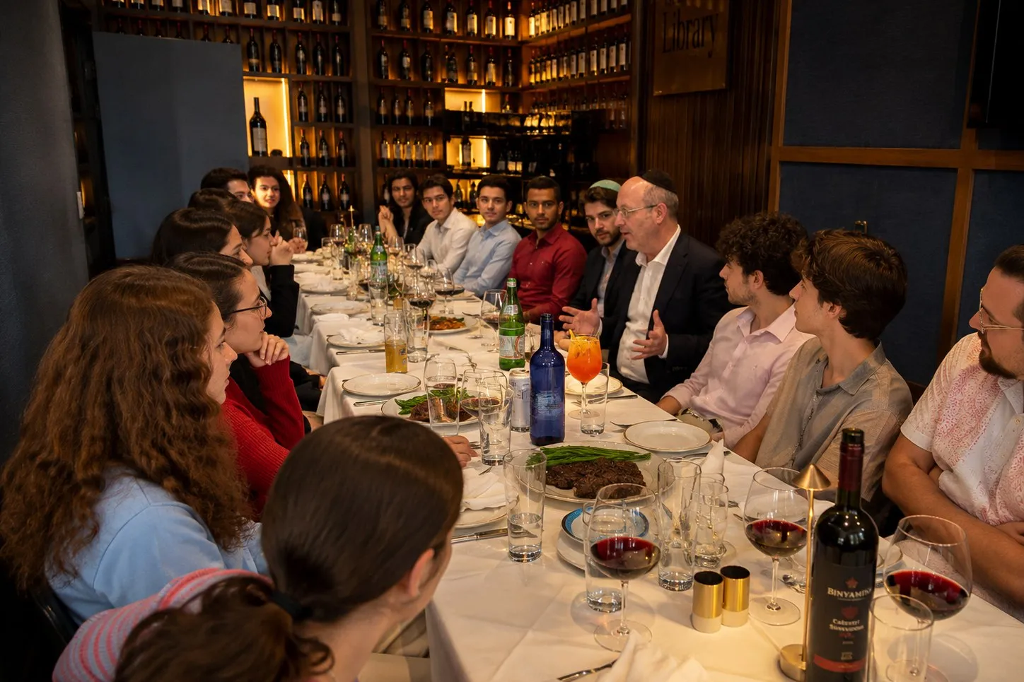 An executive speaking at a long dinner table with the whole cohort listening