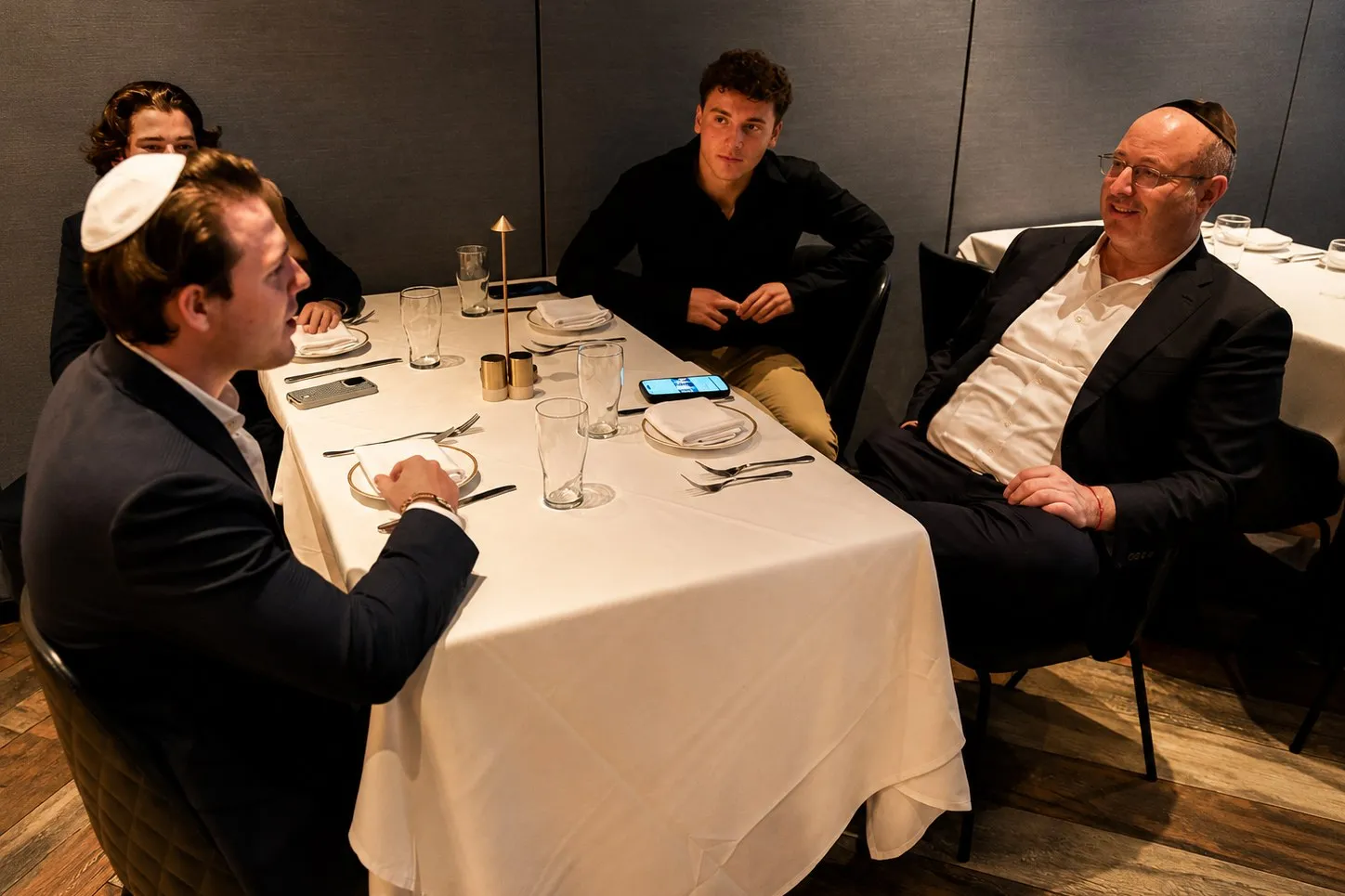 An executive and three students at a restaurant table, mid-conversation