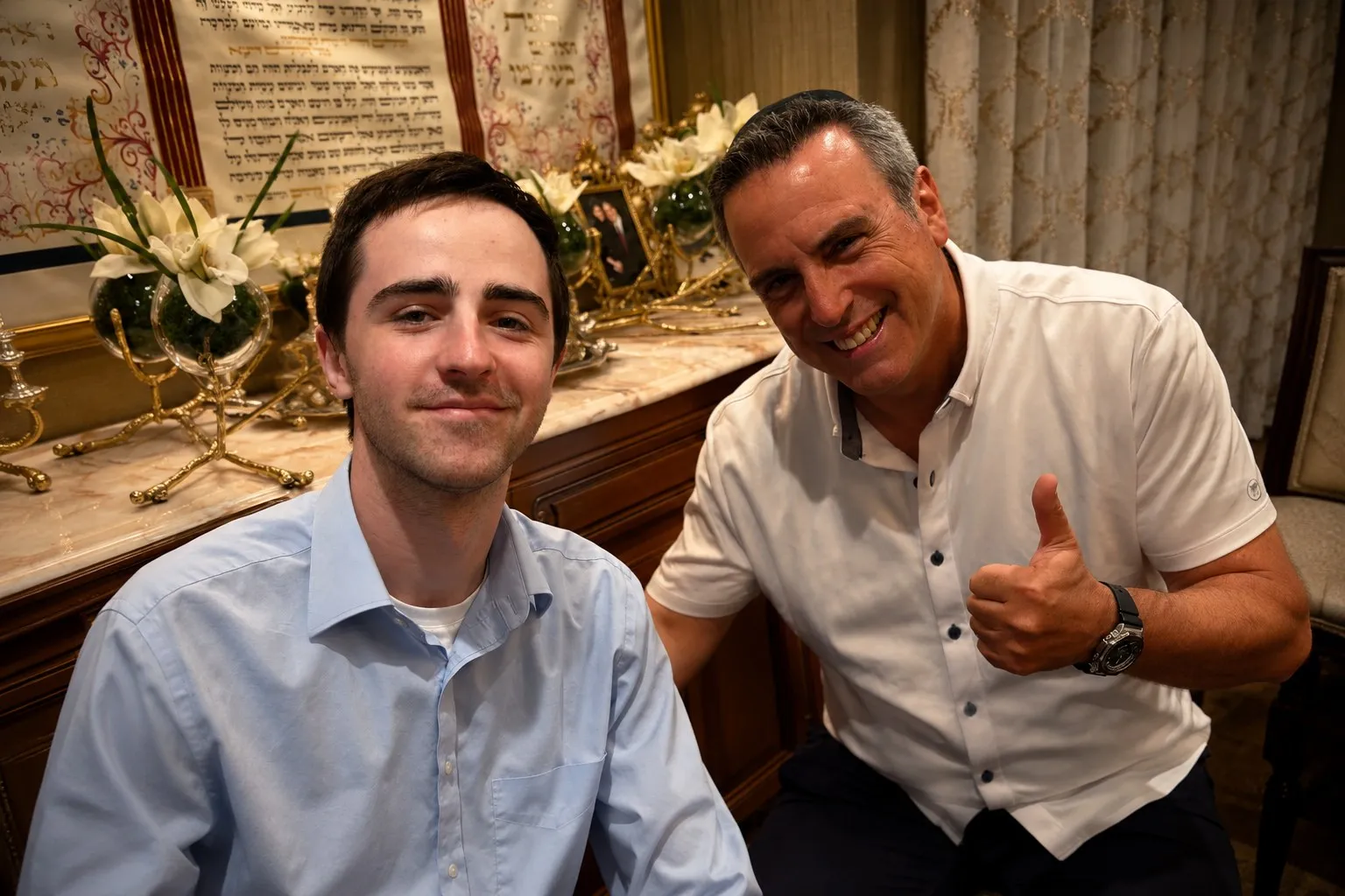 A student and an executive seated together, the executive giving a thumbs up
